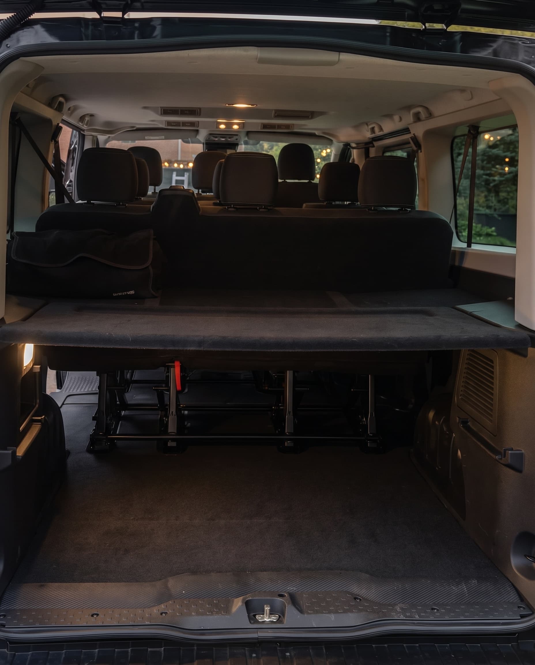 The back of the Trafic with the tailgate raised, showing the empty luggage space below a parcel shelf and the rows of seats beyond it.
