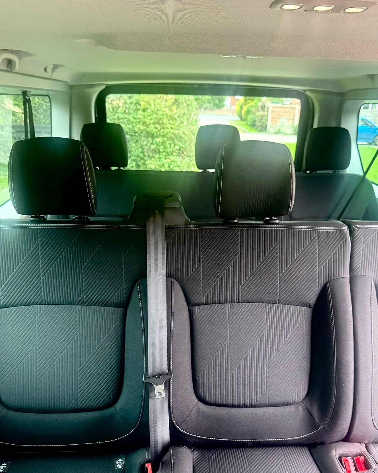 Inside the Trafic, looking back from the front: a bench of fabric seats with seatbelts and ISOFIX points, and a further row of seats behind it.